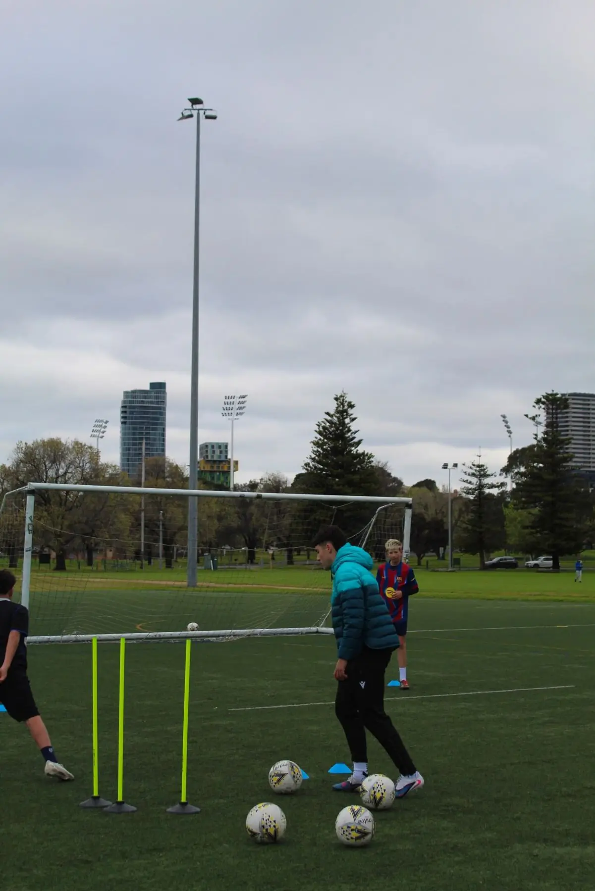 Coach Che running a ball mastery drill beside the training poles